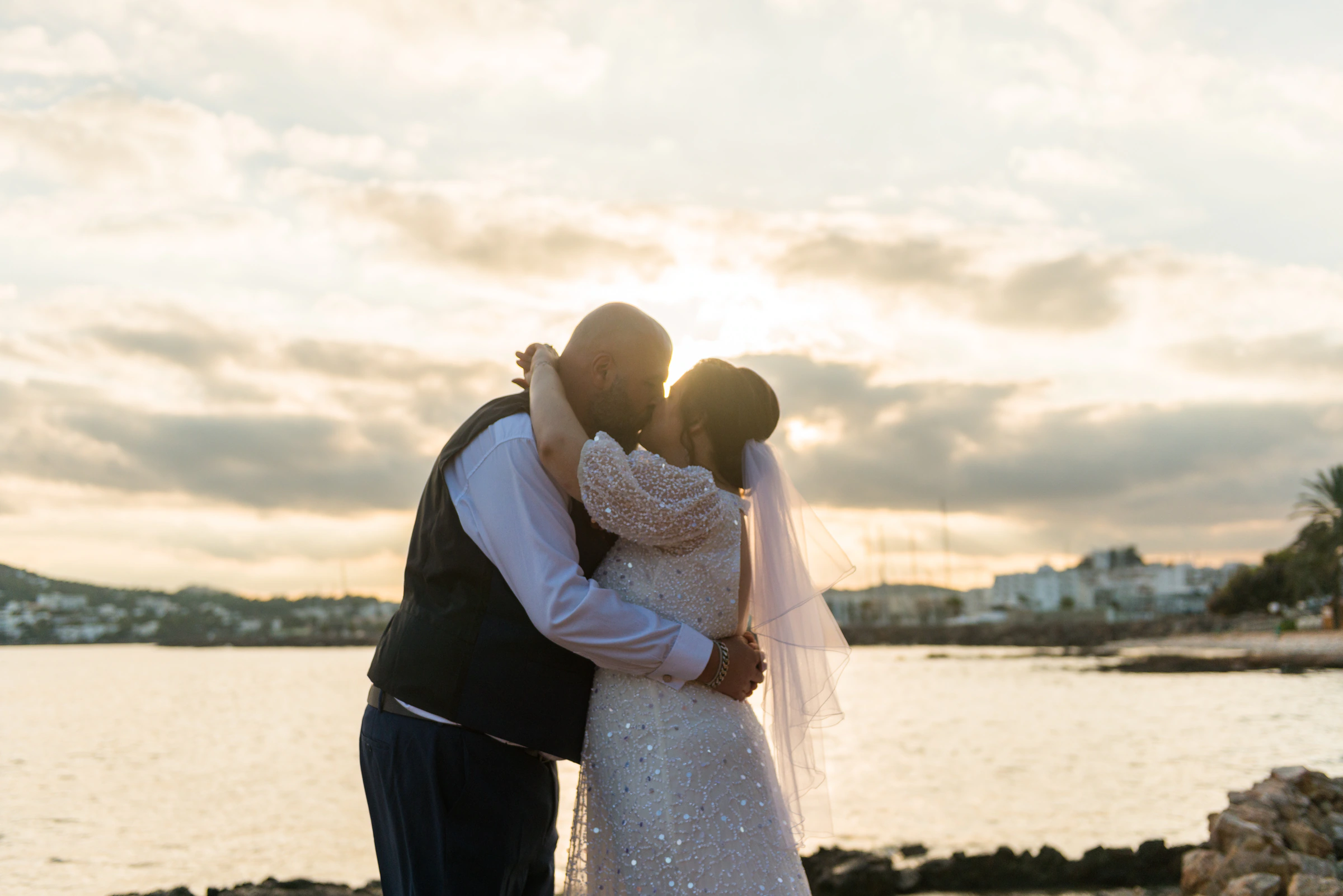Ana and Ryan embracing at sunset beside the coast in Ibiza