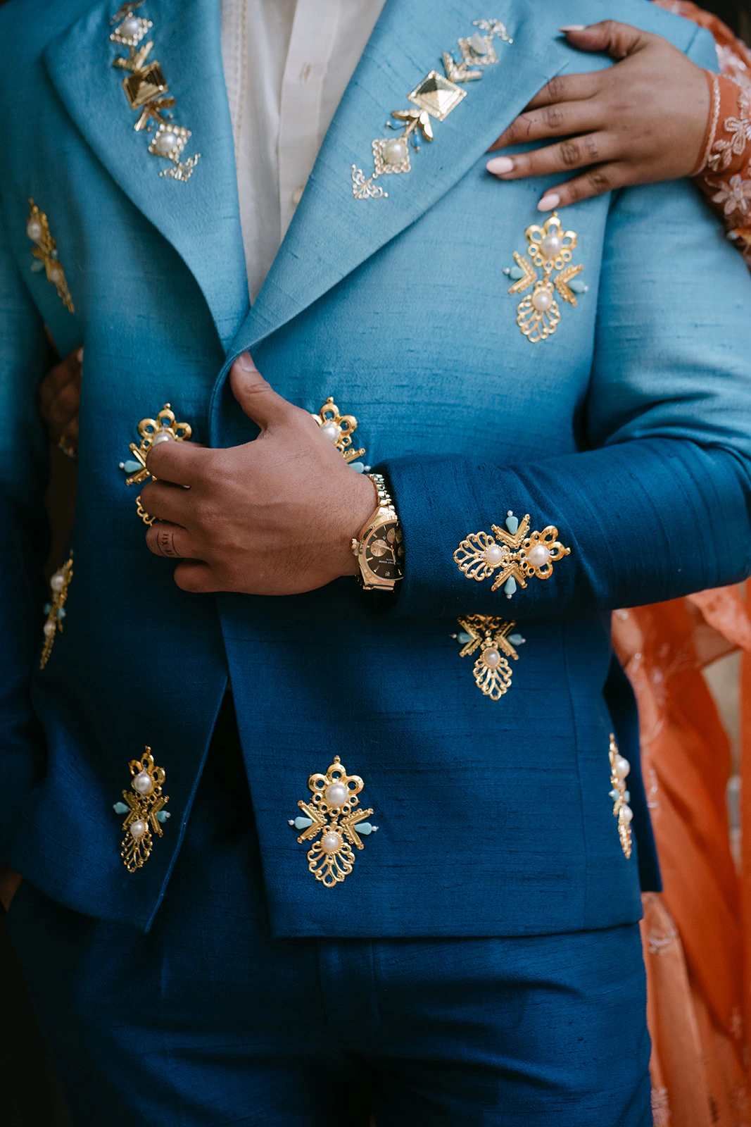 Jarryd's embroidered blue wedding jacket with Samidha's hand resting on his shoulder