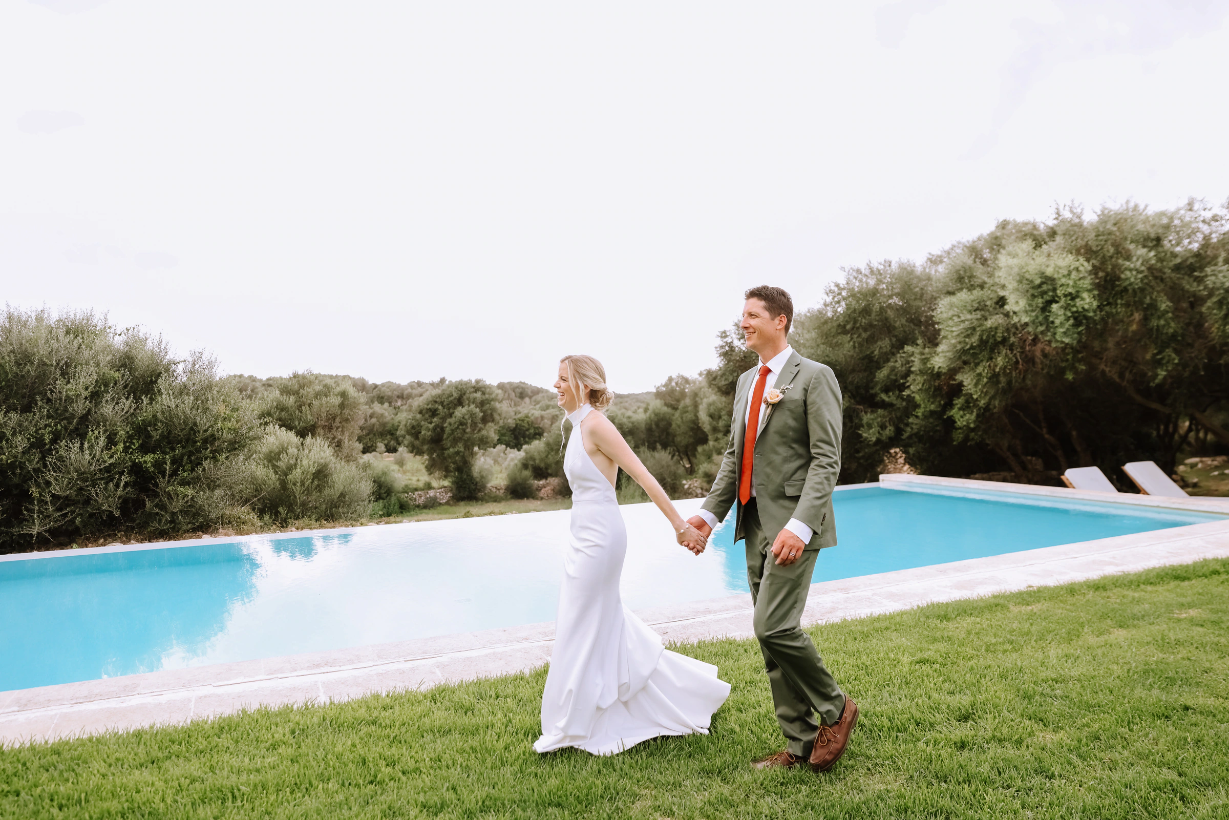 Tessa and Ryan walking beside the pool at their finca wedding in Menorca